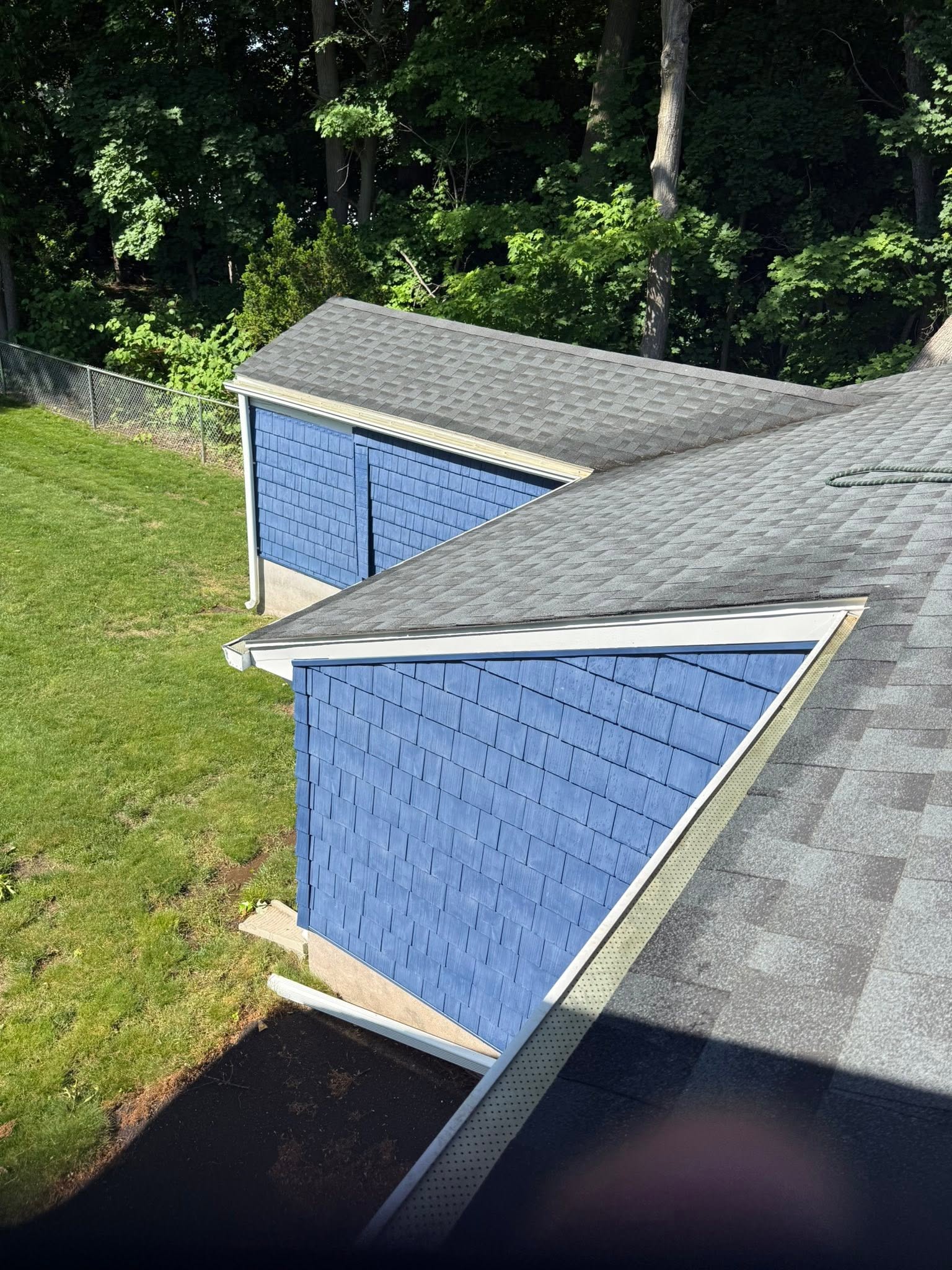 Cleaned gutters and roofline on a blue shingled house seen from the roof