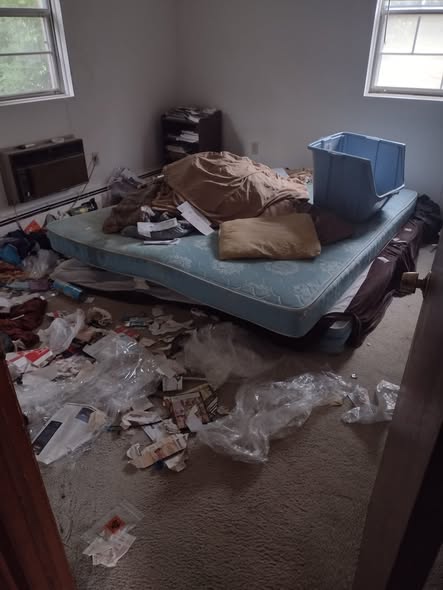 Bedroom buried in trash, a mattress and debris before cleanout